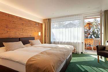 Helles Schlafzimmer mit Holzdetails und Blick auf verschneite Landschaft.