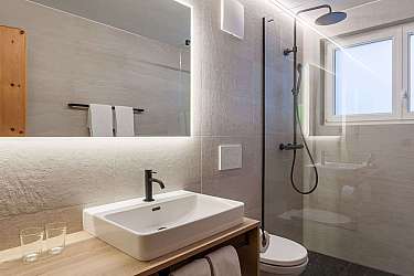 Helles Badezimmer mit Waschbecken, Dusche und Handtüchern.