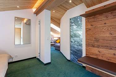 Heller Raum mit Holzdecke, Spiegel und gemütlichem Sitzbereich.