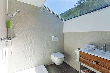 Helles Badezimmer mit Dusche, WC und Holzwaschtisch.