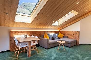 Gemütliches Wohnzimmer mit Holzdecke und modernem Mobiliar.