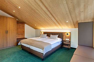 Helles Schlafzimmer mit Doppelbett und Holzverkleidung.