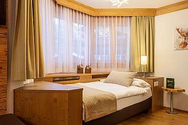 Ein helles Hotelzimmer mit Holzdetails und gemütlicher Bettwäsche.