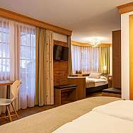 Ein helles Hotelzimmer mit Holzmöbeln und großen Fenstern.