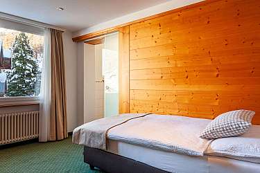 Gemütliches Schlafzimmer mit einem Bett und Blick auf verschneite Bäume.