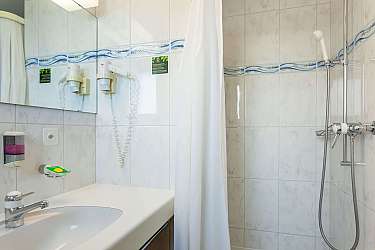 Badezimmer mit Waschbecken, Dusche und Spiegel.