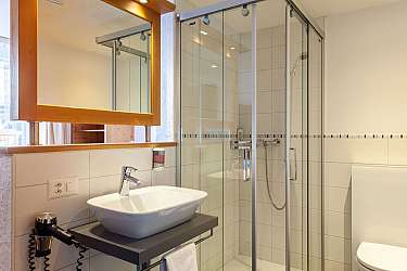 Helles Badezimmer mit Glasdusche und Waschbecken.