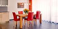 Bright dining room with wooden table and red chairs.