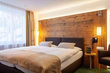 Modernes Schlafzimmer mit Doppelbett und Holzverkleidung.