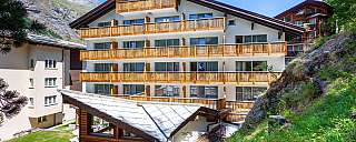 Ansicht eines modernen Hotels mit Balkonen und Berglandschaft.